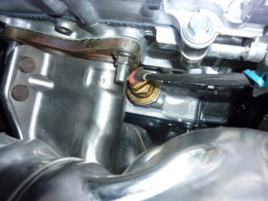 The straight plug on this block heater is close to the exhaust manifold flange.